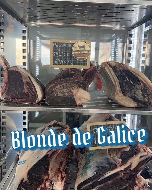 Deux étages de l'armoire de maturation : côtes de bœuf sur des grilles inox et une ardoise manuscrite « Blonde de Galice 69,90 le kg ».